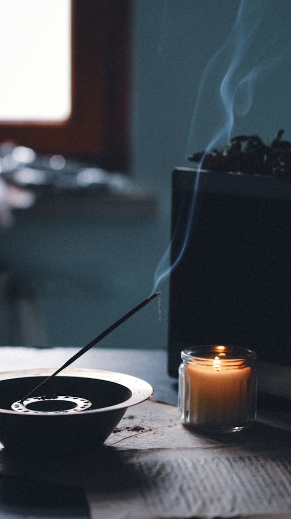 A serene indoor setup featuring a lit candle and burning incense, creating a calming ambiance.