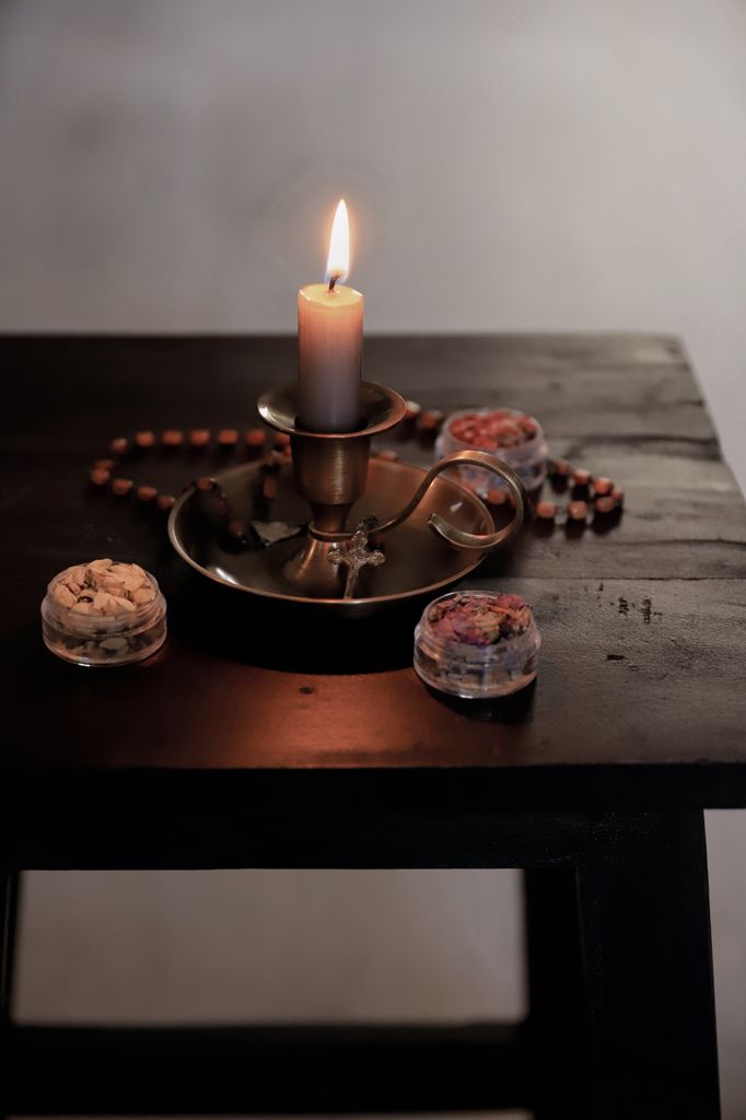 A vintage candle holder with a lit candle and decorative items on a wooden table.