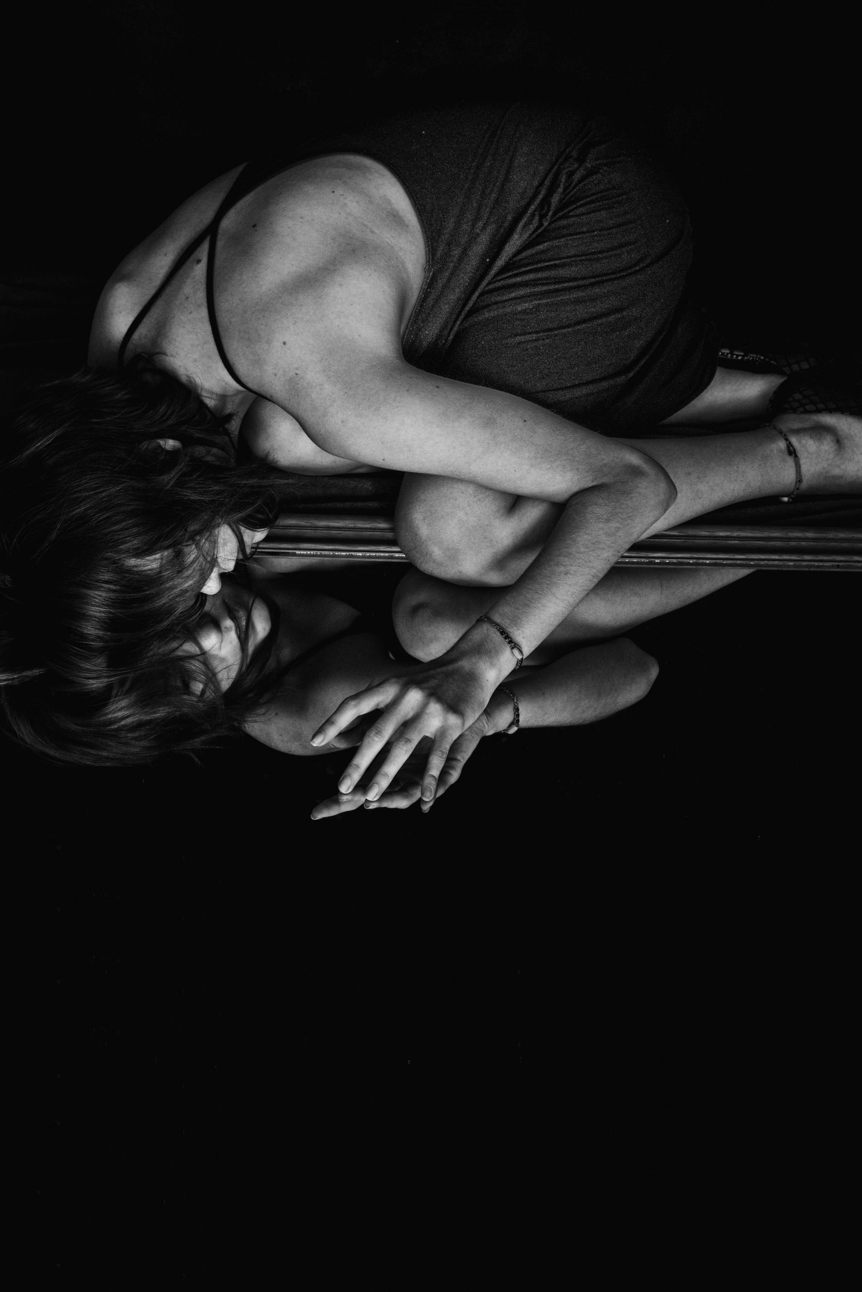 Moody black and white photo of a woman reflected in a mirror, conveying introspection.